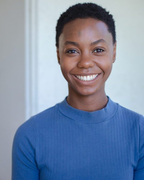 Deseree Whitt, in a blue turtleneck, smiling against a light background.