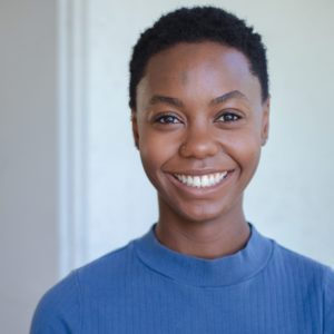 Deseree Whitt, in a blue turtleneck, smiling against a light background.