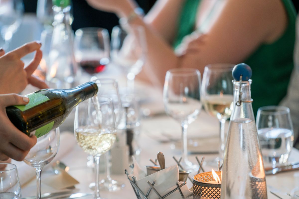 Pouring wine at a formal dinner, close-up of the glasses and candle.