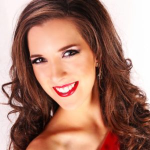 Genevieve Fulks, formally dressed in a red gown, smiling in studio lighting.