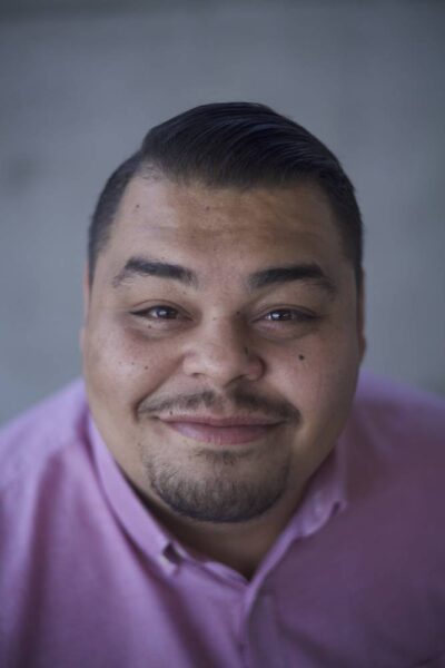 Perry Chacon, close up photo of a Latino man in a pink collared shirt.