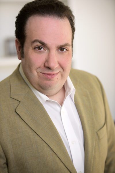 E. Scott Levin, smiling in a tan suit.