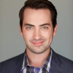 Brian Wallin, tenor, studio photo in business casual attire.