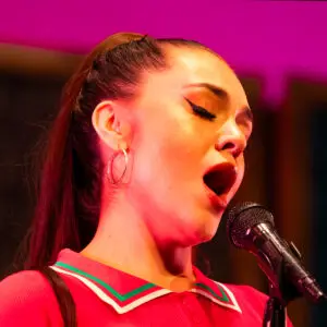 Opera Las Vegas' poster for Auction of Arias, featuring a photo of a singer in an ornate Baroque frame, held by two white-gloved auction presenters.