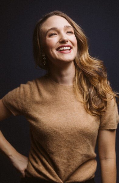Christina Pezzarossi, a caucasian woman with auburn hair, smiles upward as her face is illuminated by dramatic lighting.