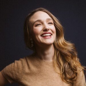 Christina Pezzarossi, a caucasian woman with auburn hair, smiles upward as her face is illuminated by dramatic lighting.