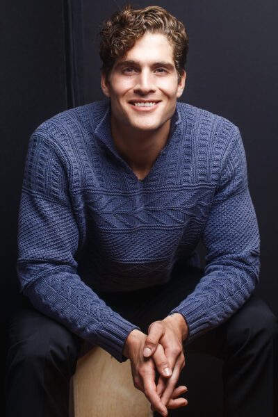 Keith Milkie, smiling in studio lighting. He wears a dark sweater.