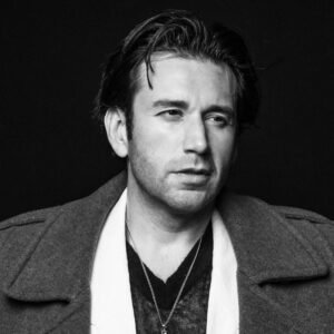 Mexican-American Tenor Joshua Guerrero photographed in studio lighting. He is dressed in stylish semi-formal attire.